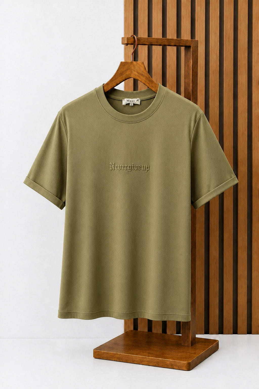 Never Give Up Embroidered Tee in Olive, on a wooden hanger